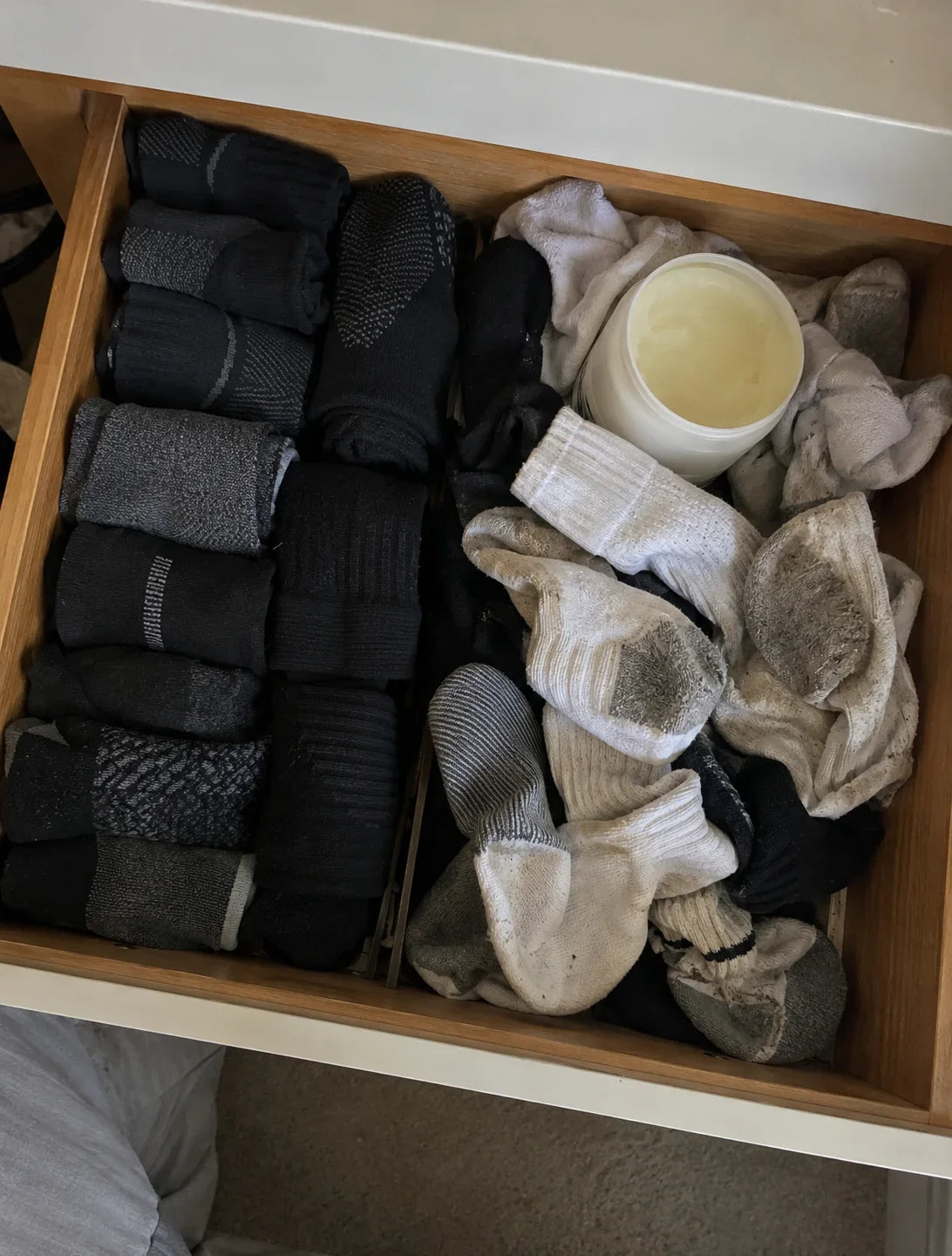 A sock drawer, neat running socks on one side and a tangle of stained old pairs on the other, a jar of petroleum jelly on top