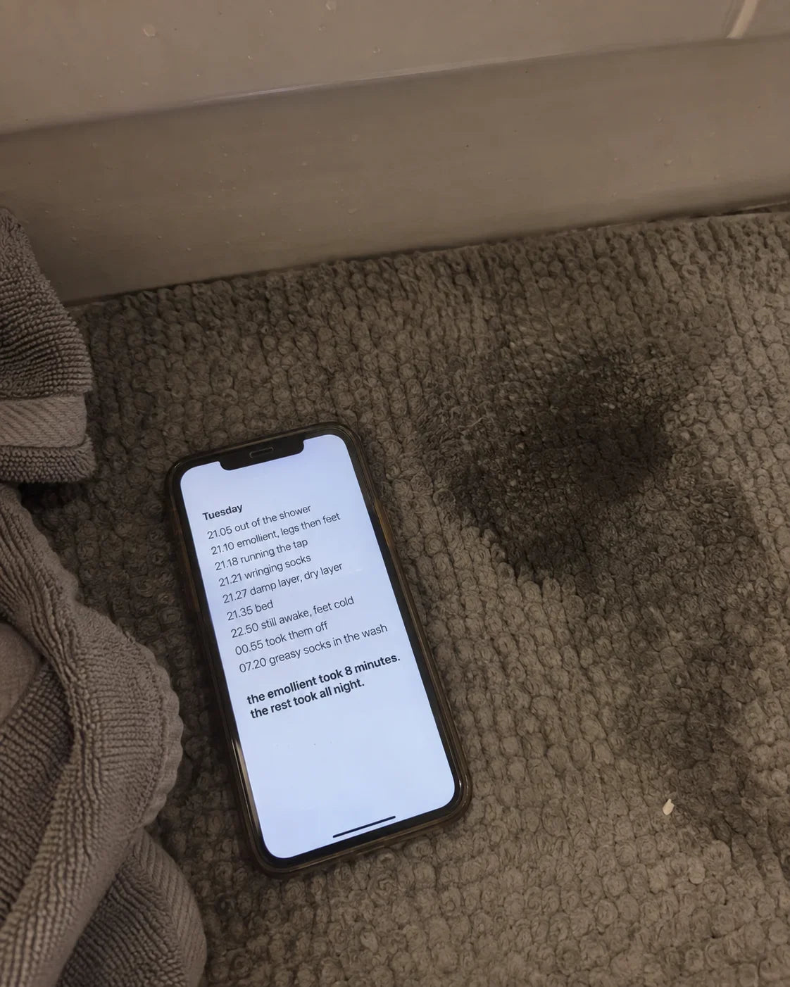 A phone lying on a bath mat, showing a notes app timeline of one evening