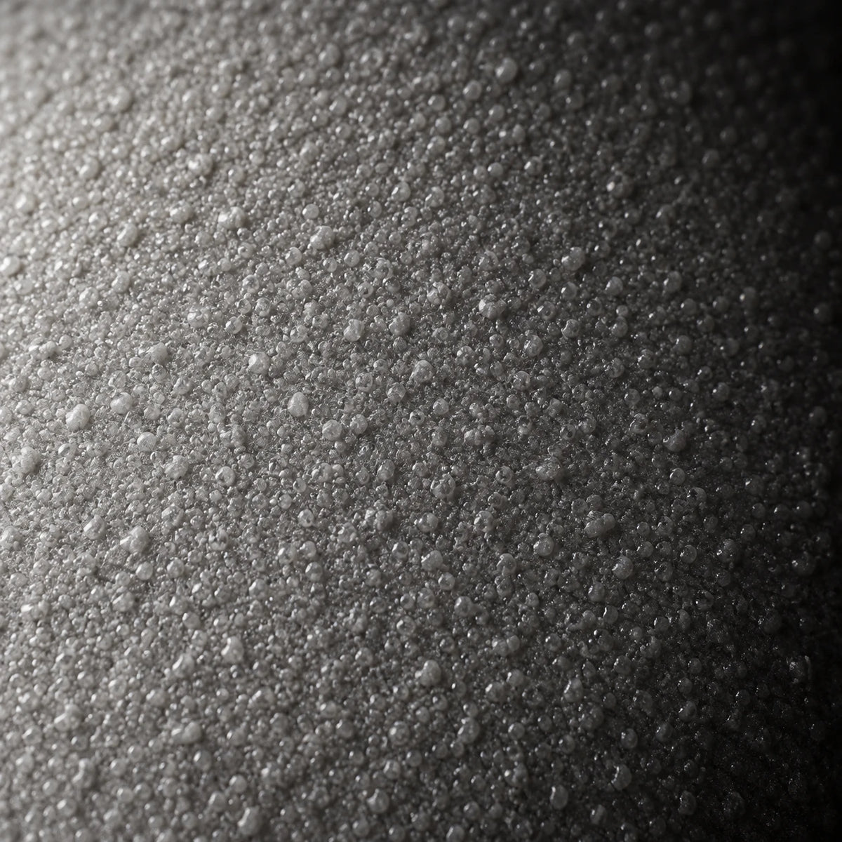 Bonded silicone layer at 3–5×, raking light at 15°, black ground.